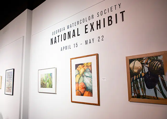 National Watercolor Society Exhibit 2026 entrance to the roush gallery while walls with exhibit name in black and three watercolor paintings below